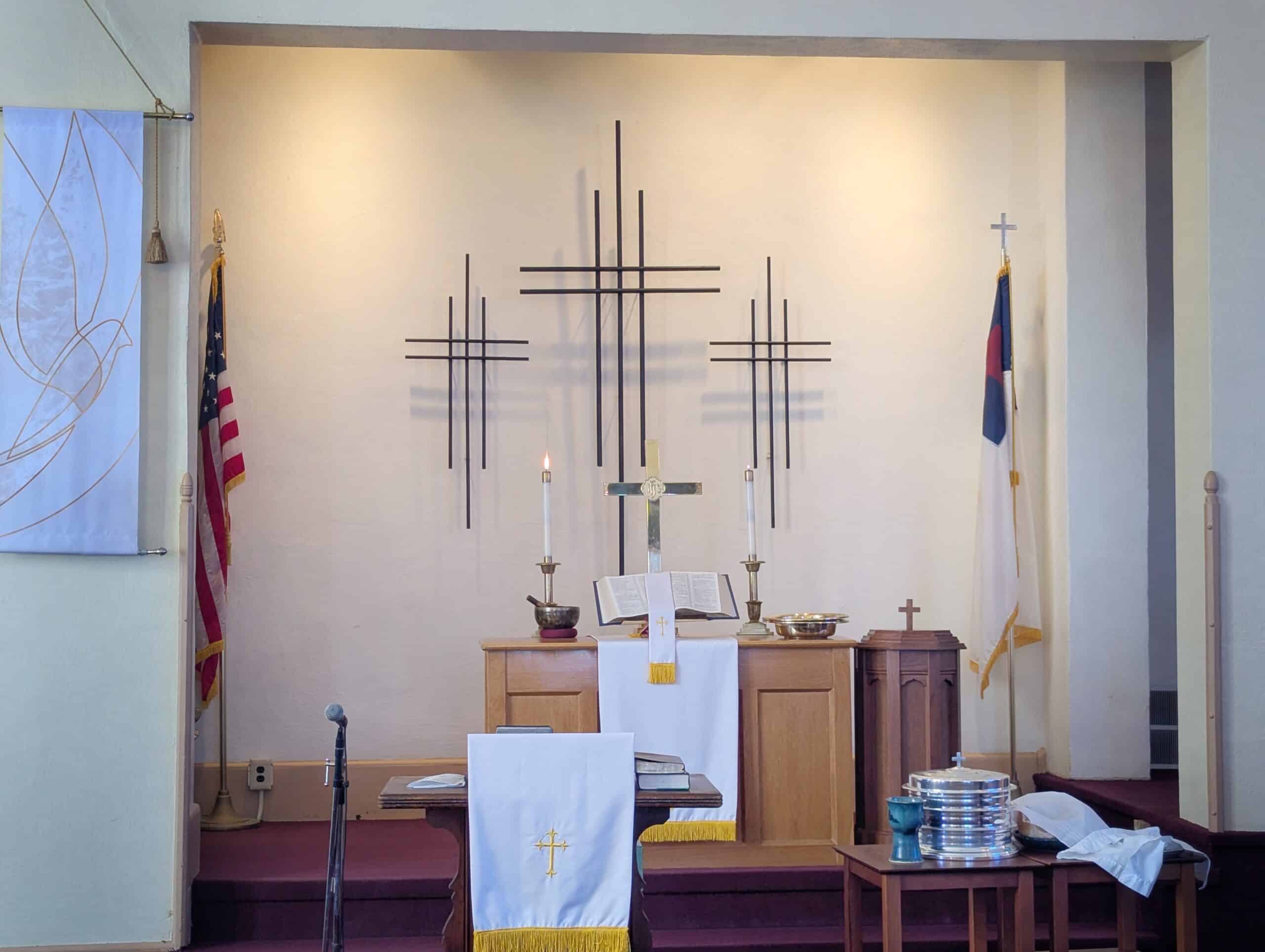 Altar table, candles, and three crosses on the chancel wall