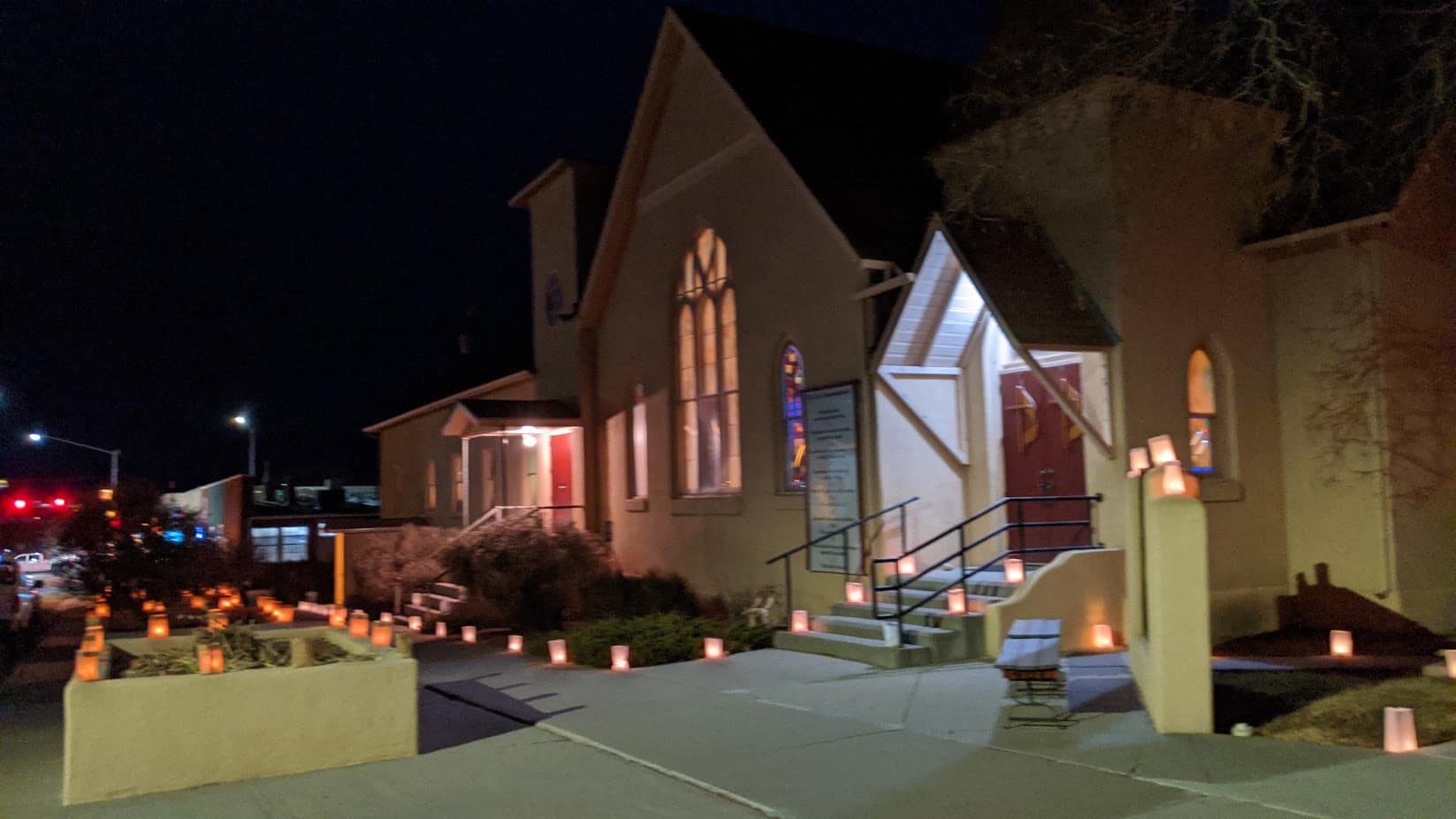 The church building on Chaco Street at night, lined with luminarias