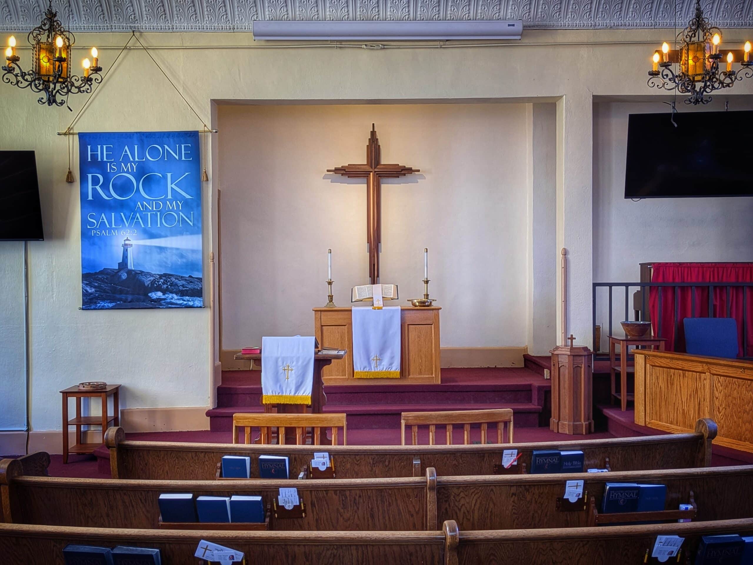 The altar, wooden cross, and pews in the sanctuary