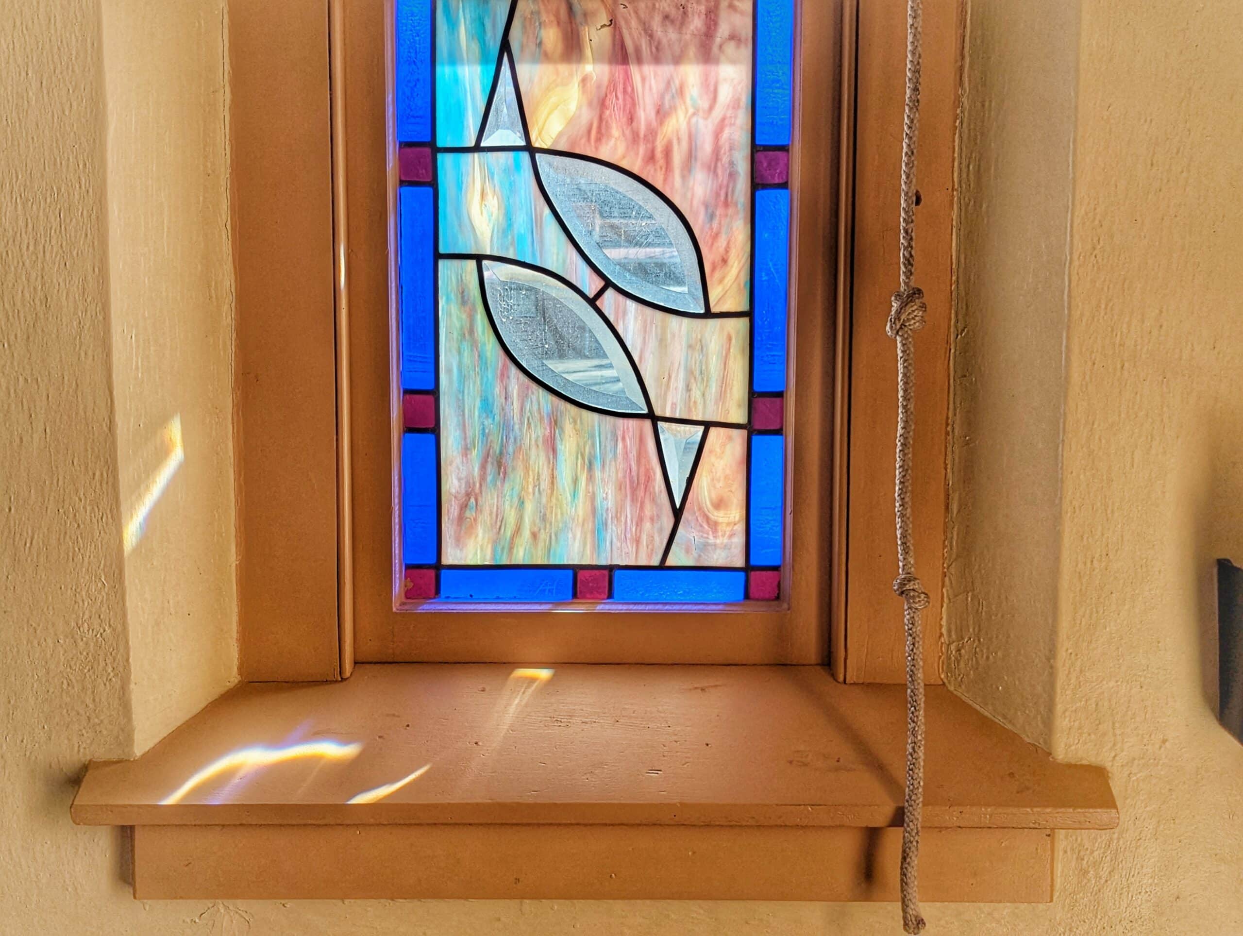 A stained-glass window and the bell rope